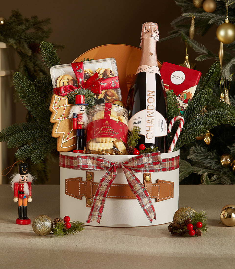 Festive Christmas hamper with Chandon Rosé, shortbread cookies, chocolates, and gingerbread in round white box with plaid