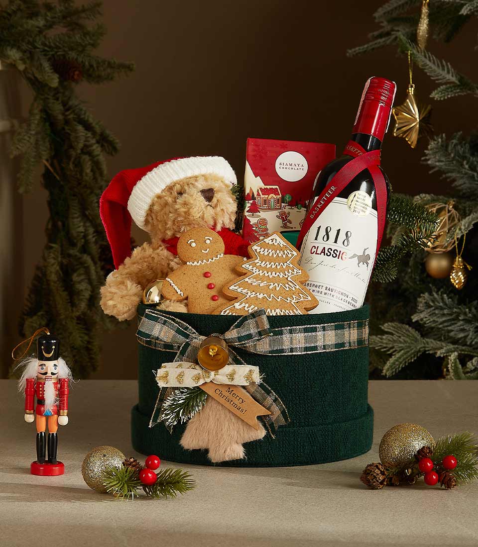 Luxury Christmas gift box with teddy bear, red wine, gingerbread cookies, and festive ornaments