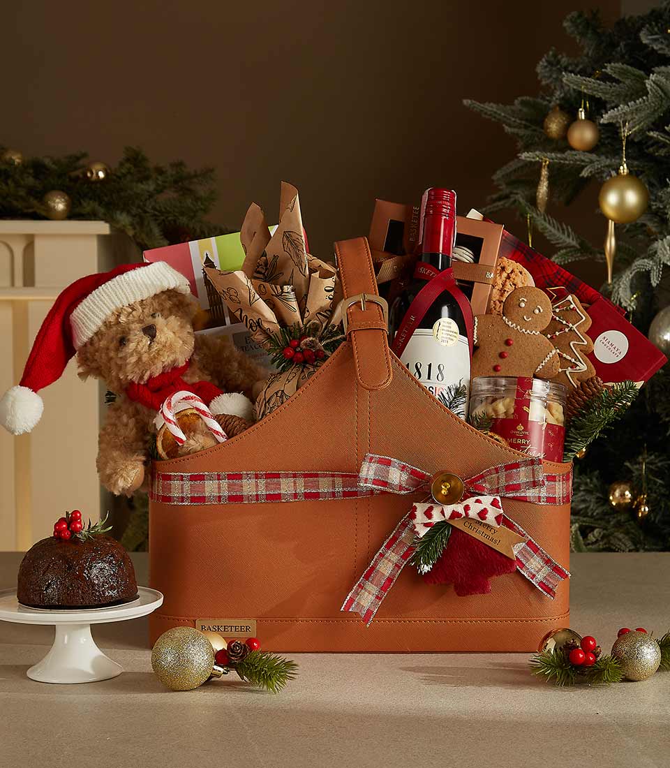 Luxury brown leather Christmas gift basket with red wine, teddy bear, gingerbread, and festive treats