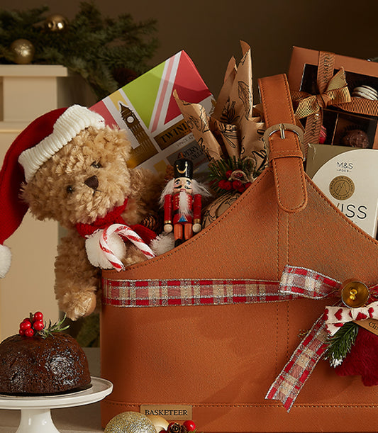 Festive leather holiday gift basket with teddy bear, nutcracker, tea, and Christmas pudding for classic British celebrations