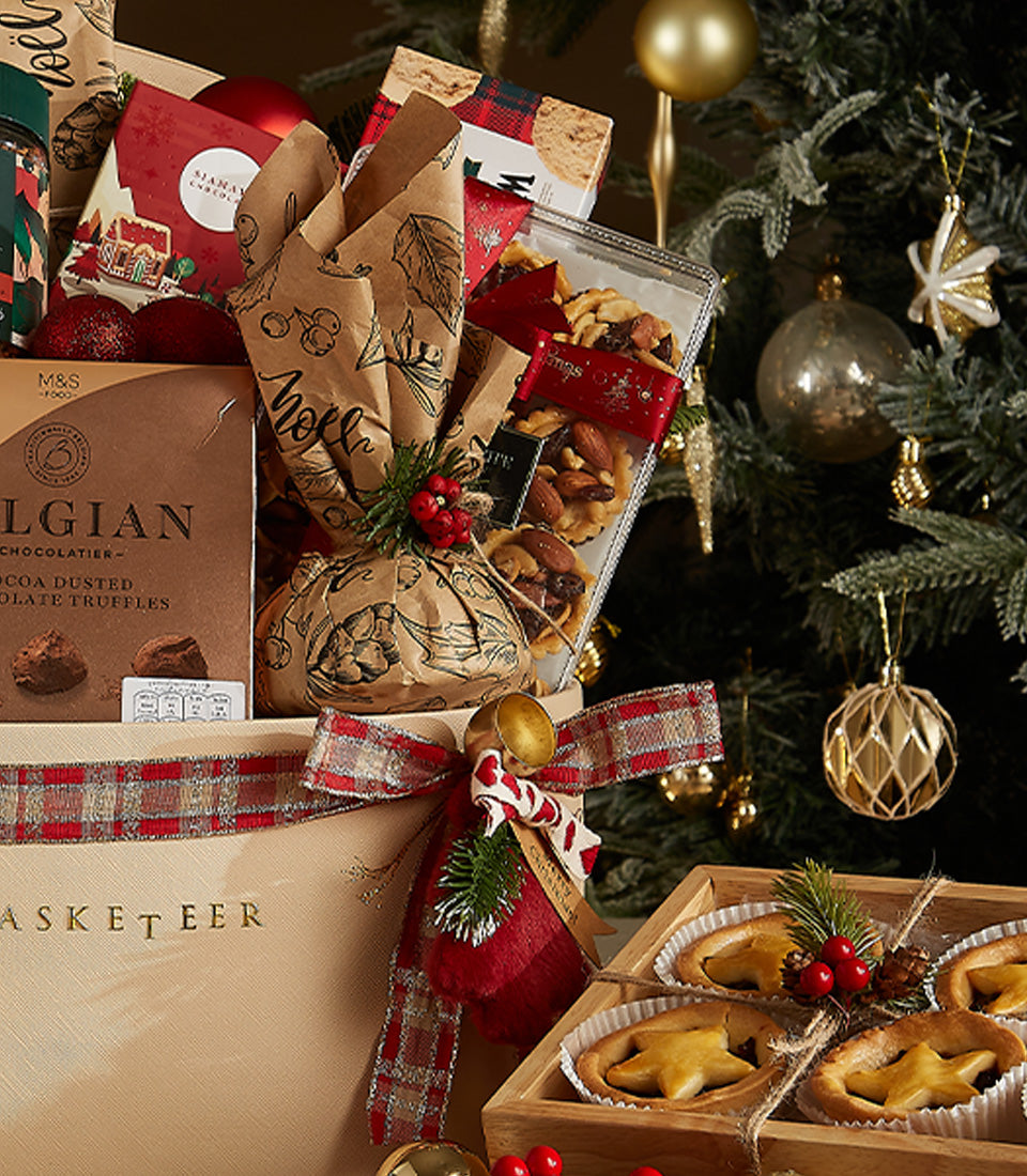 Festive gold gift hamper with Belgian chocolates, mince pies, and gourmet treats tied with red plaid ribbon