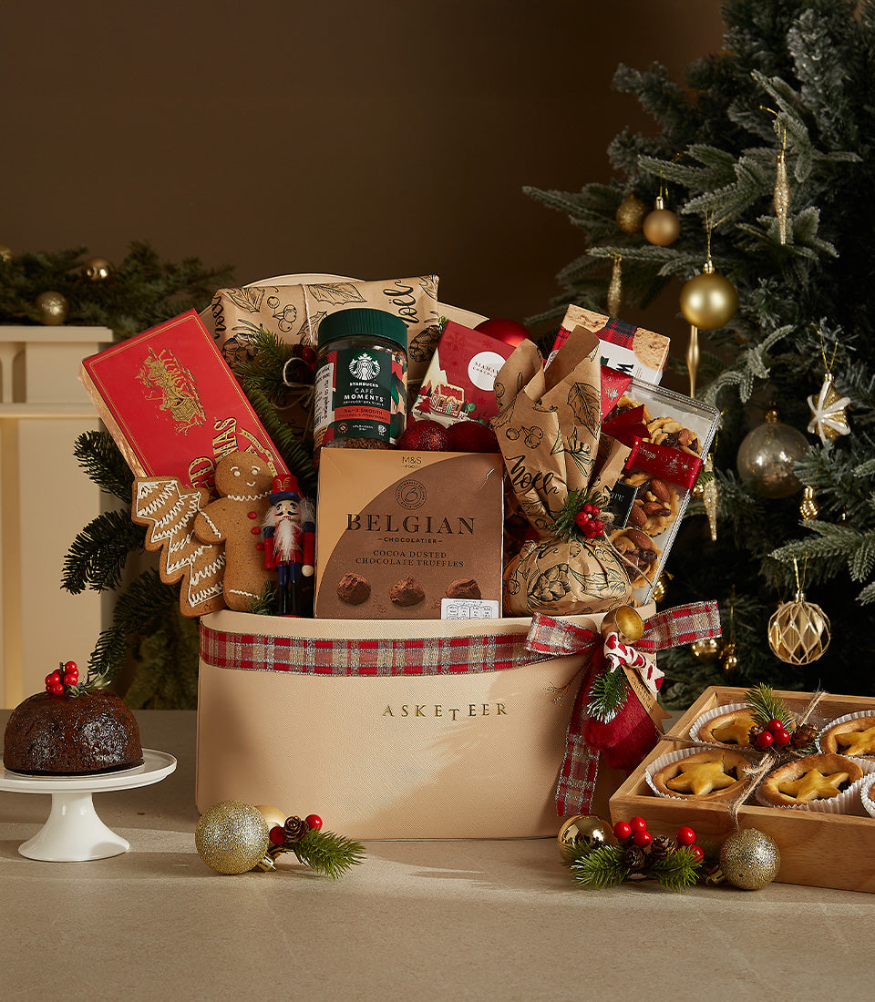 Festive luxury gift hamper with gingerbread, chocolate truffles, holiday coffee, and mince pies in cream basket with plaid