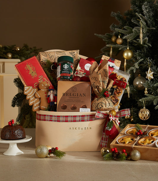Festive luxury gift hamper with gingerbread, chocolate truffles, holiday coffee, and mince pies in cream basket with plaid