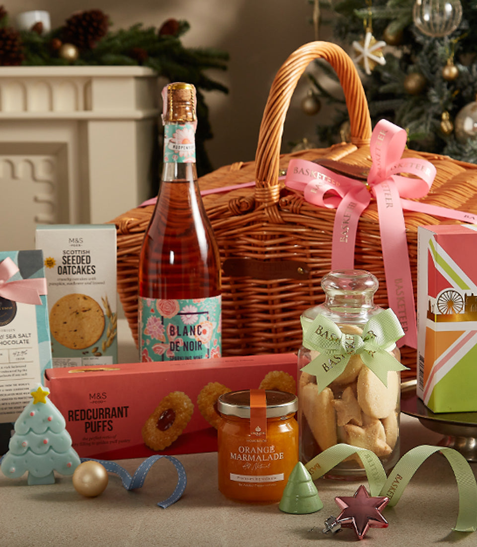 Festive wicker picnic basket with Blanc de Noir sparkling wine, oatcakes, marmalade, and star cookies for Christmas