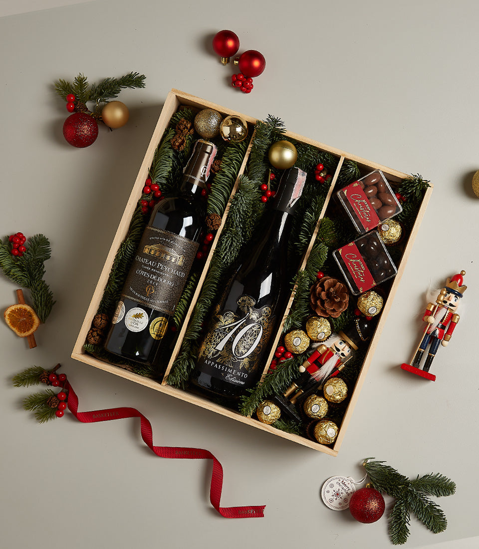 Luxury red wine and chocolate Christmas gift box with gold-wrapped Ferrero Rocher, pine-lined wooden compartments, and