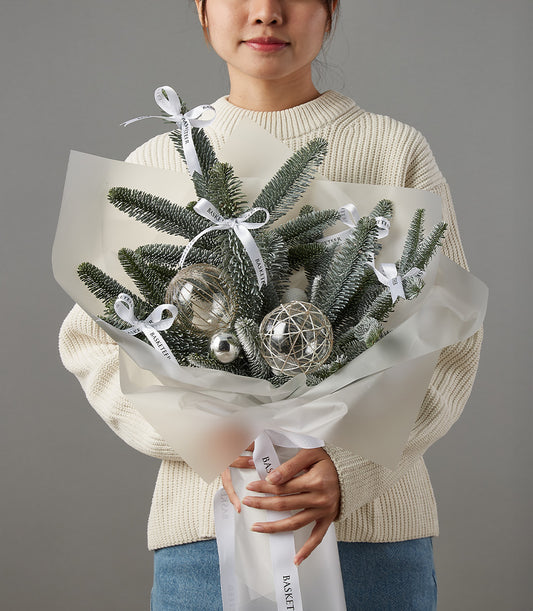Festive evergreen Christmas bouquet with frosted branches, silver ornaments, and white satin ribbon