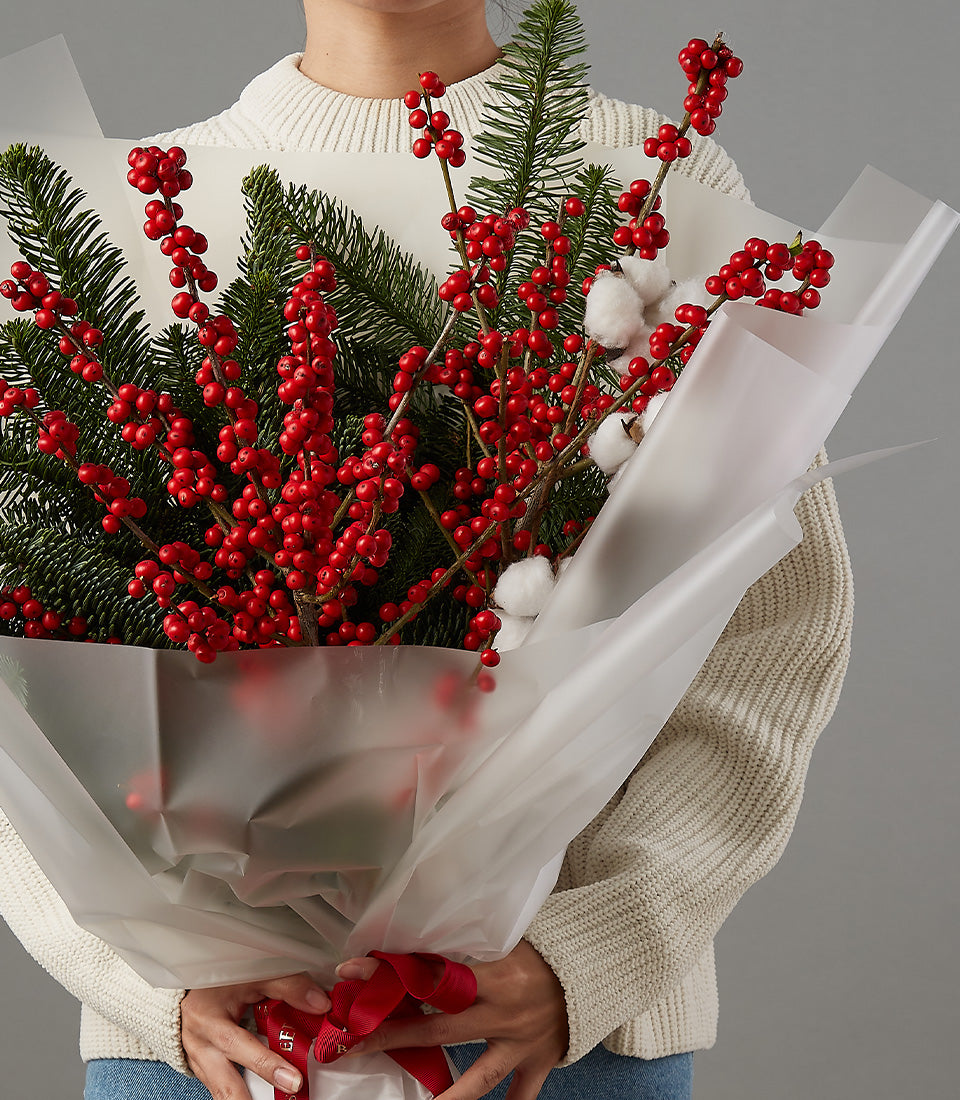 Festive red berries, white cotton, and evergreen Christmas bouquet with red ribbon