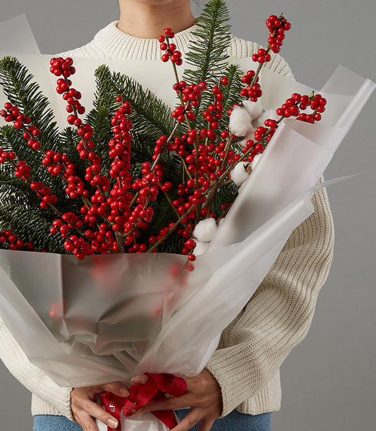 Festive red berries, white cotton, and evergreen Christmas bouquet with red ribbon