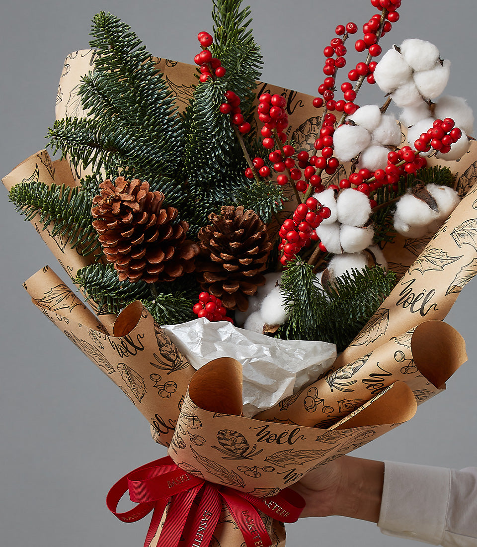 Festive red berry and white cotton Christmas bouquet with pine and pinecones, kraft paper wrapped