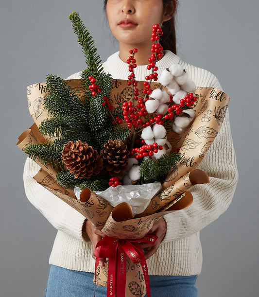 Festive Christmas flower bouquet with red berries, fir branches, pinecones, and cotton bolls in kraft paper wrap