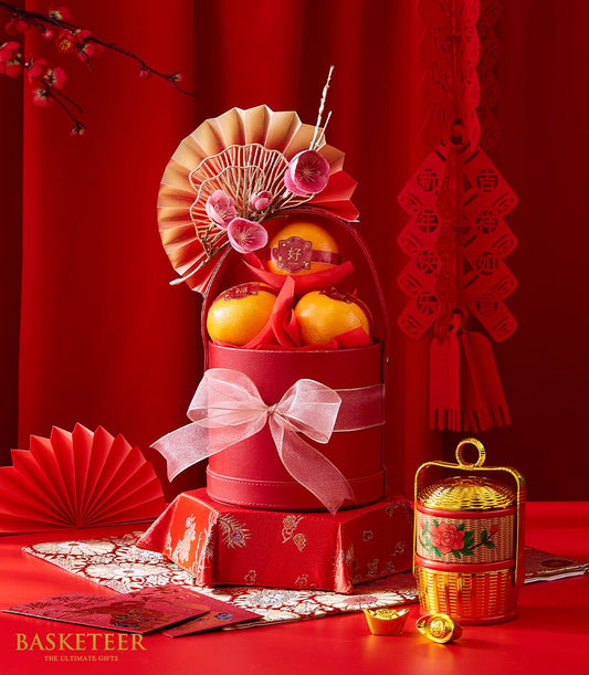 Red mandarin gift box with tangerines, golden fan, and lucky gold ingots for Chinese New Year celebrations
