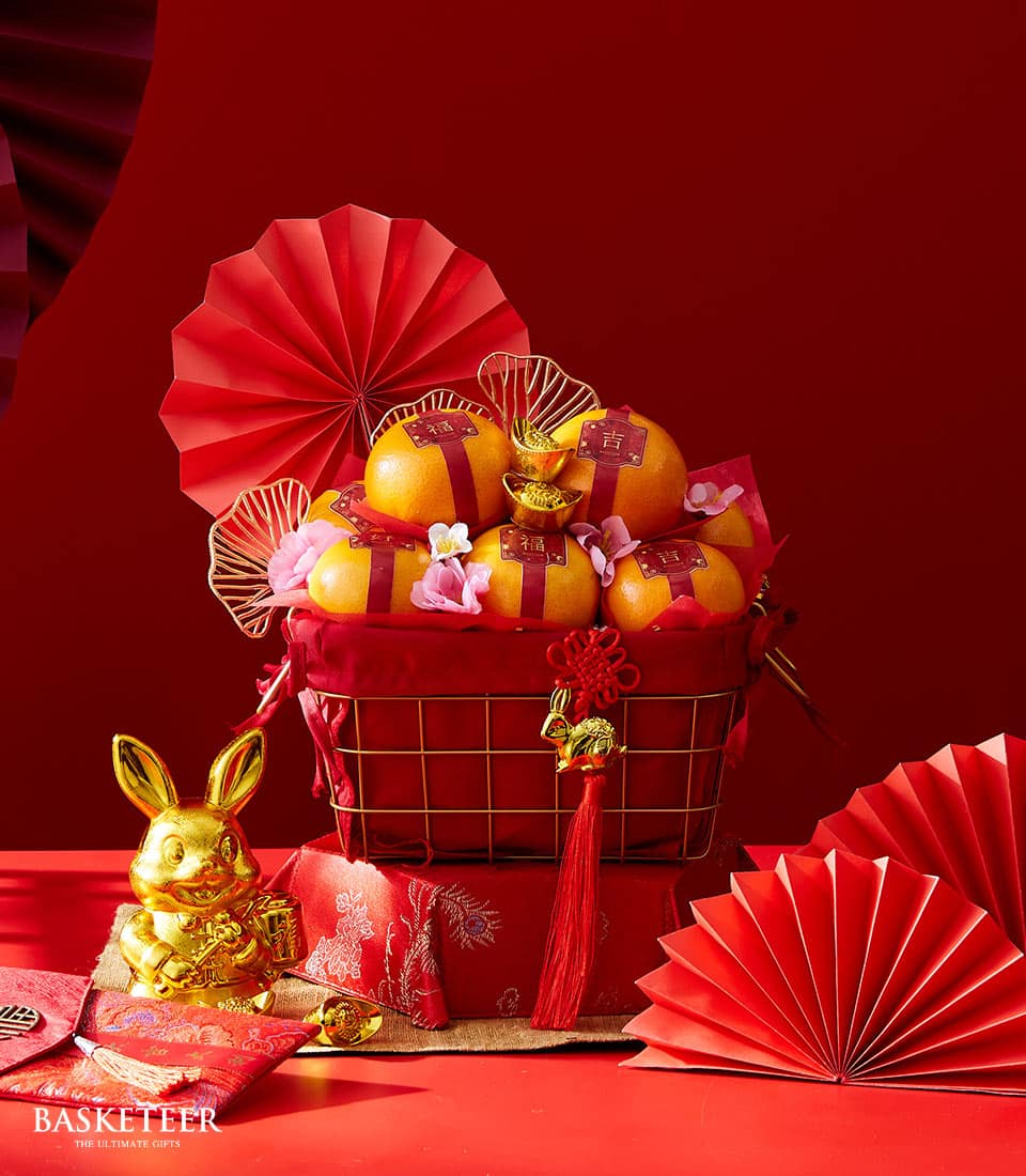 Red and gold mandarin orange gift basket with Chinese New Year prosperity charms and festive decorations