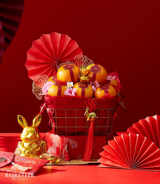 Red and gold mandarin orange gift basket with Chinese New Year prosperity charms and festive decorations