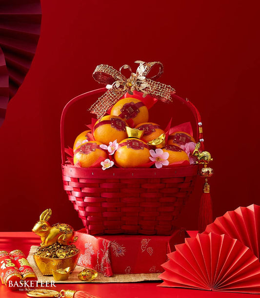 Festive red gift basket with mandarin oranges, gold ribbon bow, and Chinese New Year prosperity decorations