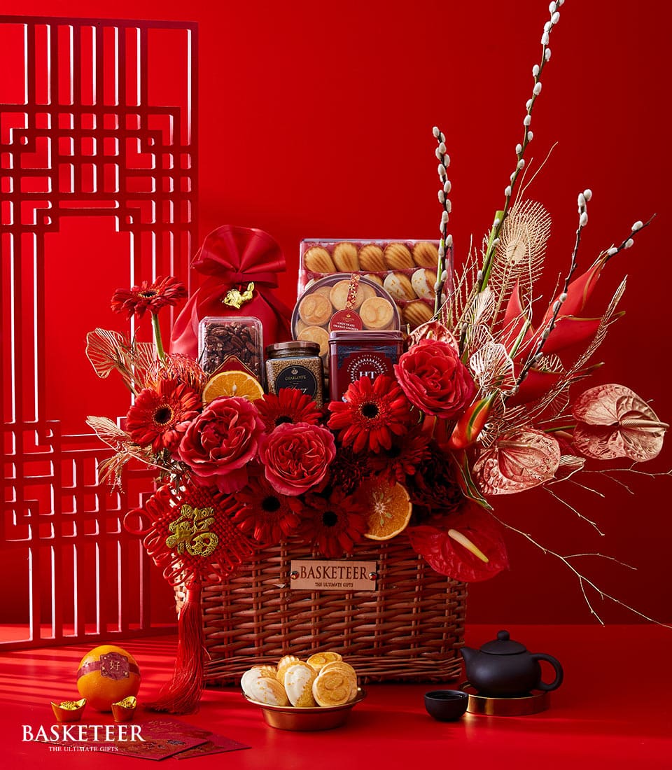 Lunar New Year luxury gift basket with red roses, gerbera daisies, gold foliage, artisan cookies, and festive accents
