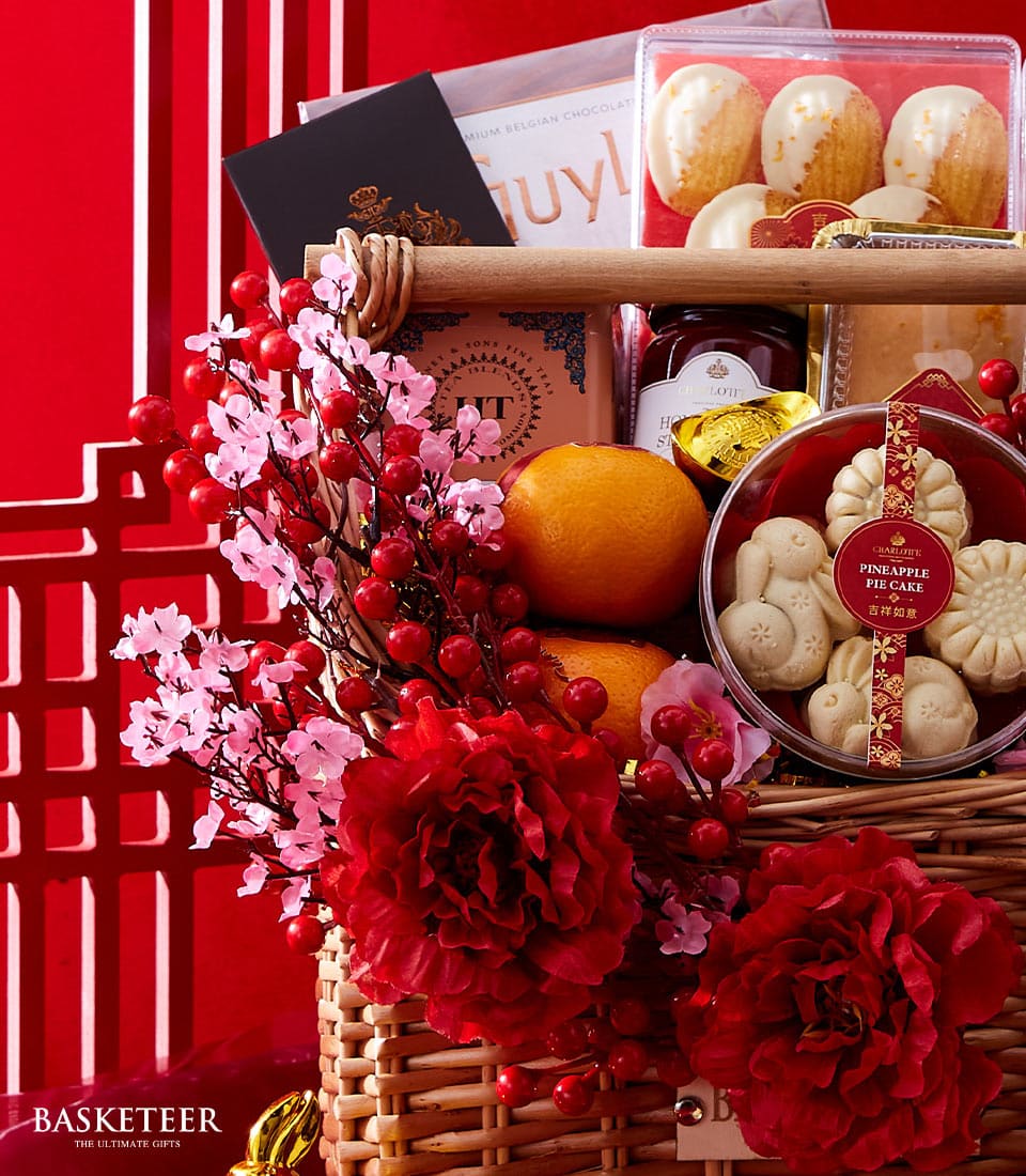Lunar New Year woven basket with Belgian chocolates, mandarins, pineapple pie cake, and red florals on festive striped red