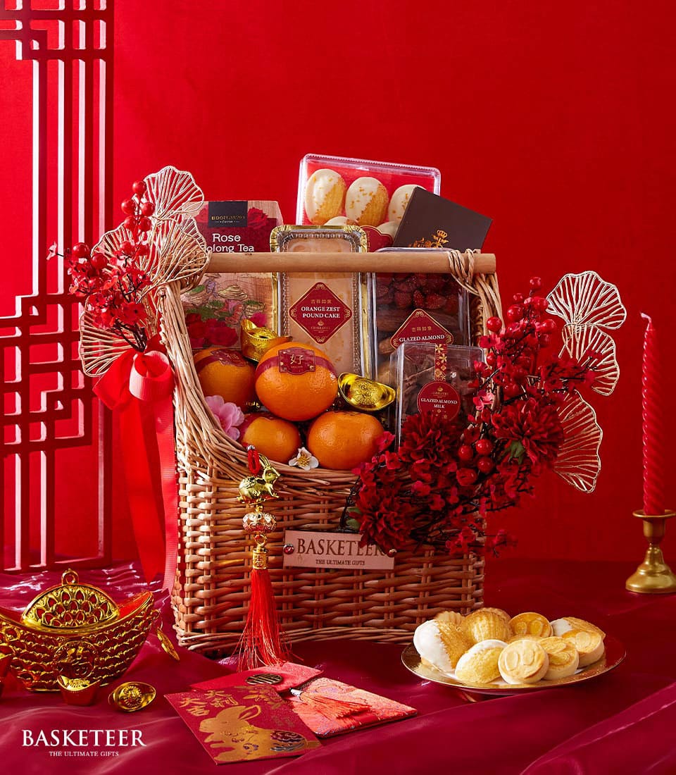 Festive Chinese New Year citrus and sweets gift hamper with tea, pound cake, glazed almonds, fresh oranges, and red ribbon