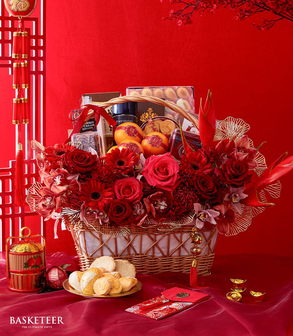 Luxury CNY gift basket with red roses, gerbera daisies, orchids, gourmet treats, gold accents, and festive red envelopes