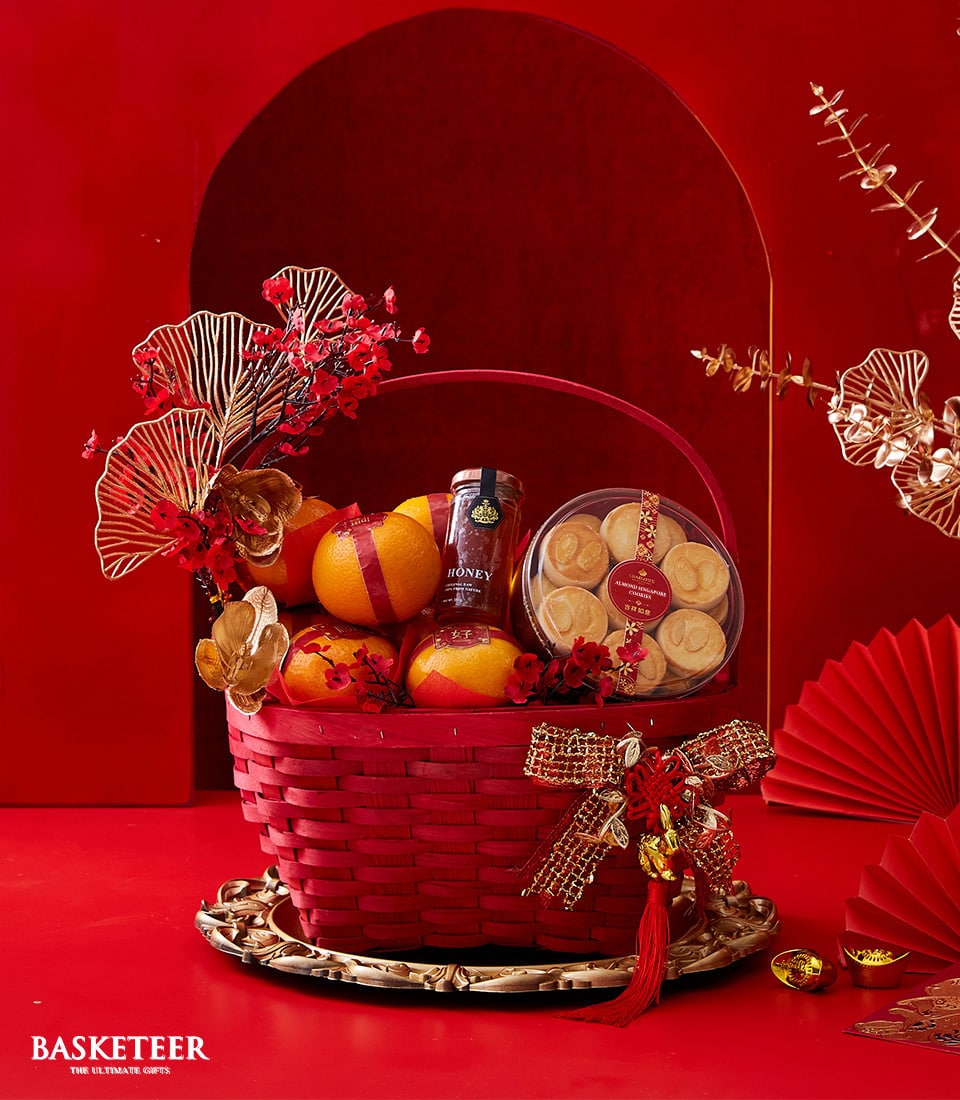 Luxury red and gold Chinese New Year gift basket with oranges, honey, almond cookies, and festive ornaments