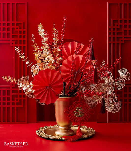 Lunar New Year floral arrangement with red branches and golden foliage in ornate gold vase