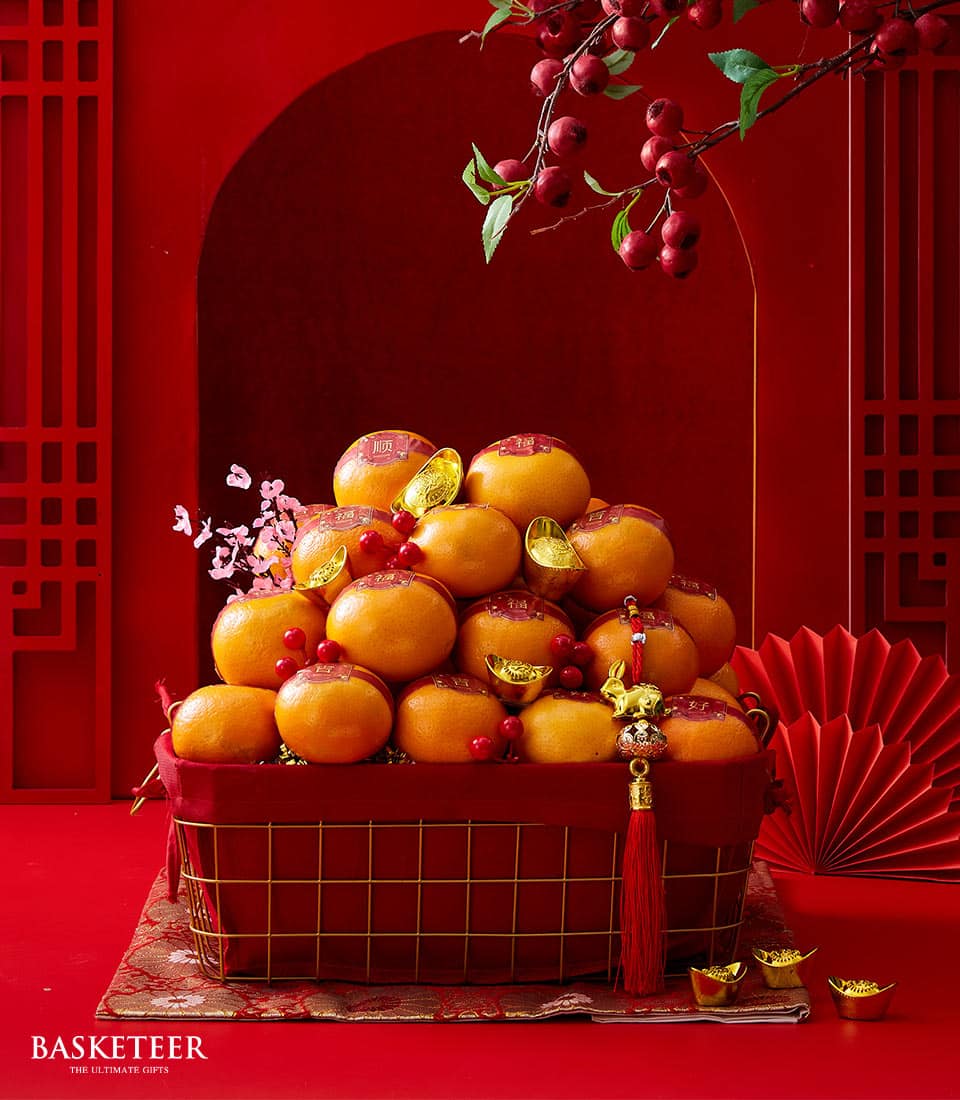 Abundant gold wire gift basket overflowing with bright mandarins, red fabric lining, and lucky gold ingots for Chinese New
