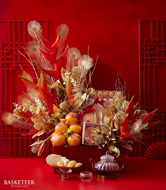 Luxury Chinese New Year gift basket with red helicorum, gold accents, prosperity oranges, madeleines, and gourmet tea service