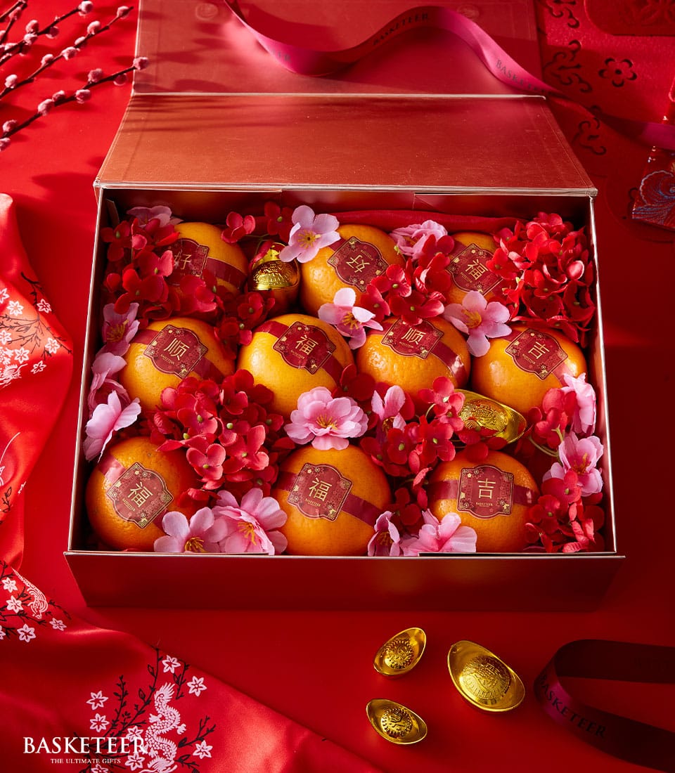 Red luxury gift box with nine auspicious oranges, red silk bands, gold characters, and festive florals for Chinese New Year