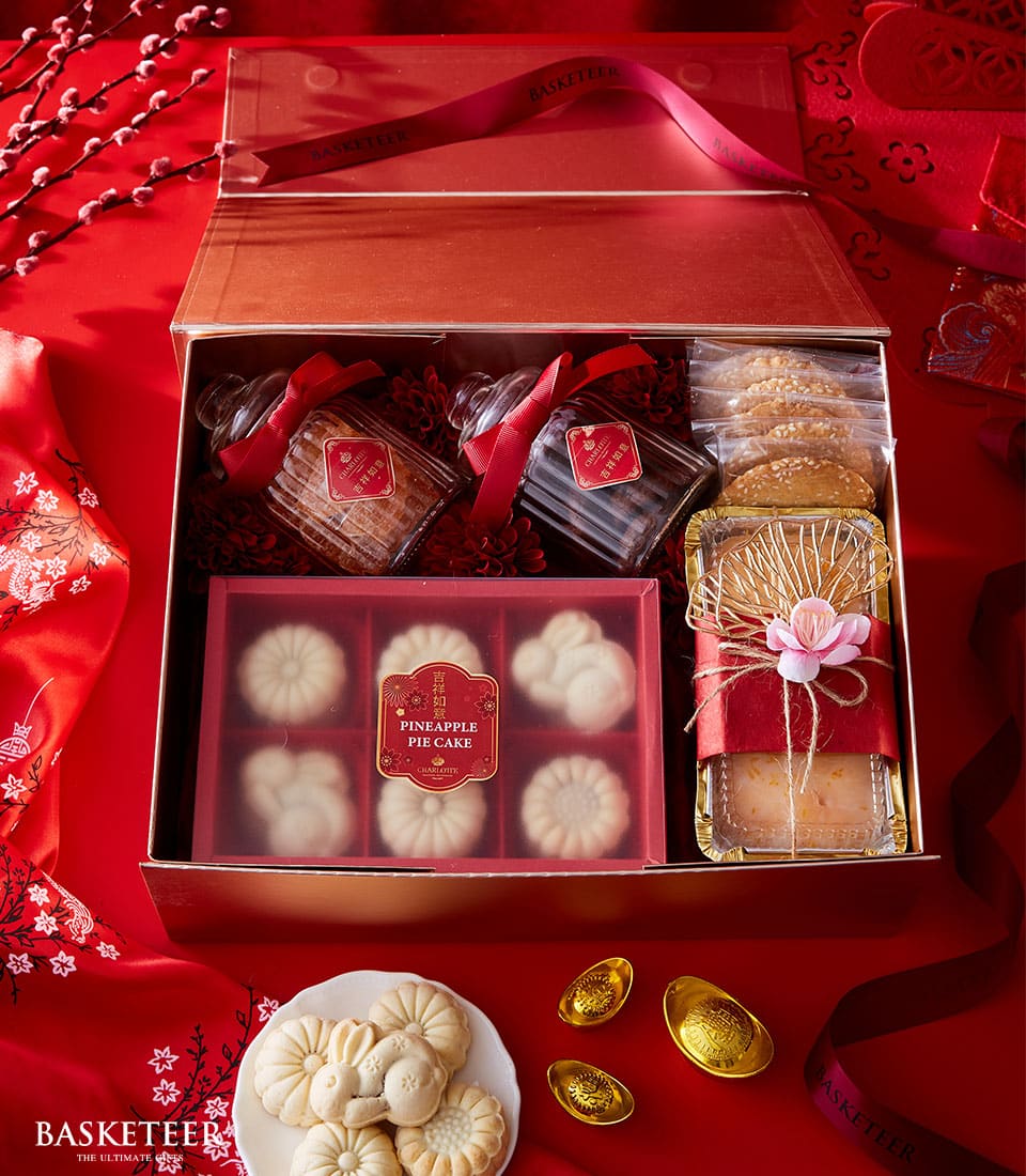 Luxurious Lunar New Year treats gift box with cookies, pineapple cakes, and festive gold accents on red silk