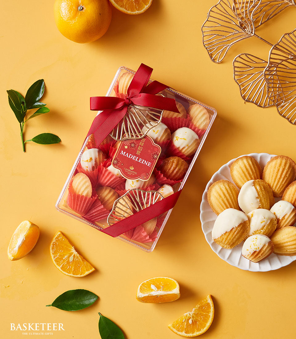 Mandarin Dream Blossom madeleines gift box with white-frosted pastries, oranges, and red ribbon for Chinese New Year