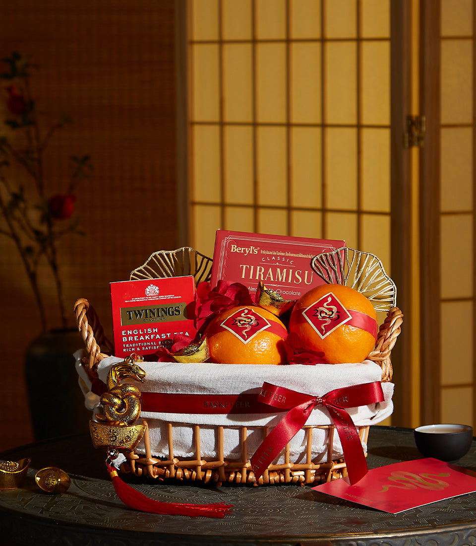 Festive orange mandarin and gourmet gift basket with tiramisu chocolate, English breakfast tea, and red ribbon for Chinese