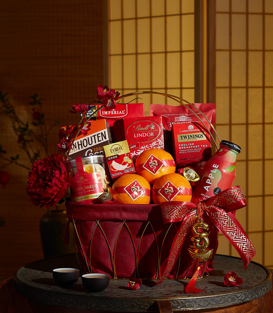 Basketeer Chinese New Year gift basket: oranges, Lindor chocolates, and gourmet treats nestled in a red velvet lined hamper with gold detail. Premium hamper delivery Thailand.