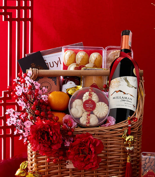Festive red gift basket with red wine, chocolates, madeleines, honey, and pineapple cakes for Chinese New Year celebrations