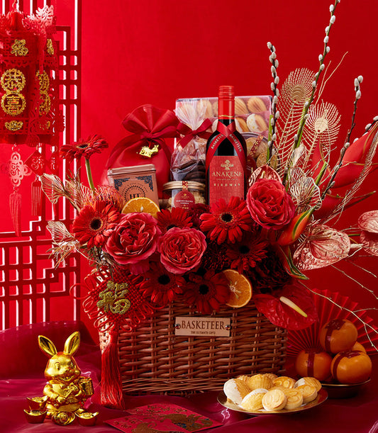 Lunar New Year luxury gift basket with red wine, fresh roses, gerbera daisies, almond crackle, and festive gold accents