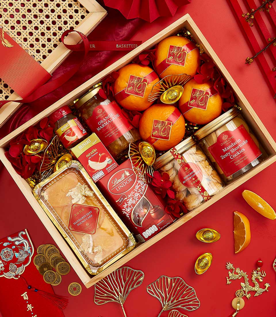 Basketeer premium hamper delivery Thailand: A wooden gift box brimming with oranges, marmalade, cookies, and chocolates for a luxurious CNY corporate gift.