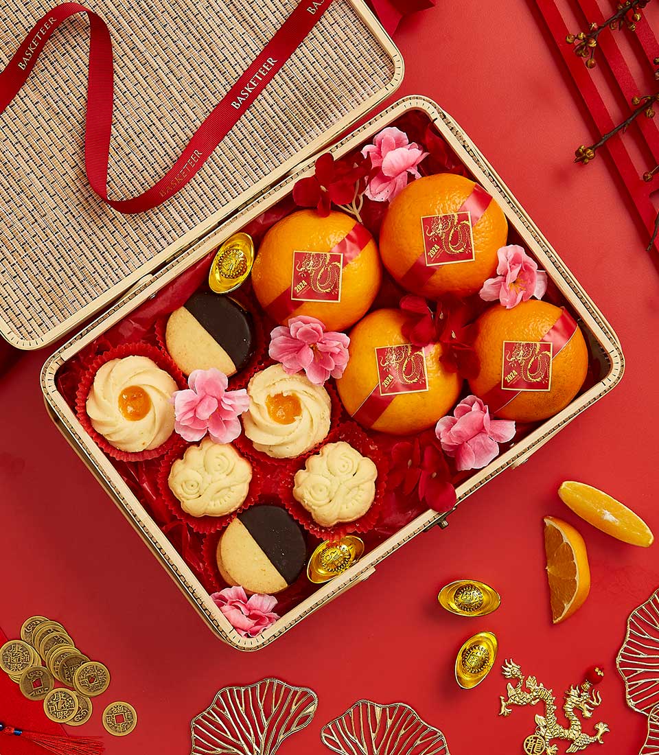 Basketeer CNY gift. Wicker hamper with Lunar New Year mandarin oranges, festive cookies, and gold ingots. Premium hamper delivery in Thailand.