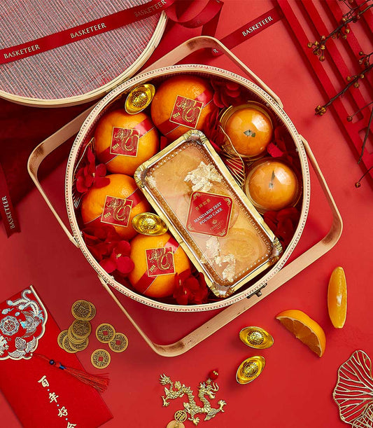 Basketeer CNY gift: oranges and Mandarin Fest Pound Cake in a round hamper with red ribbon. Premium hamper delivery Thailand.