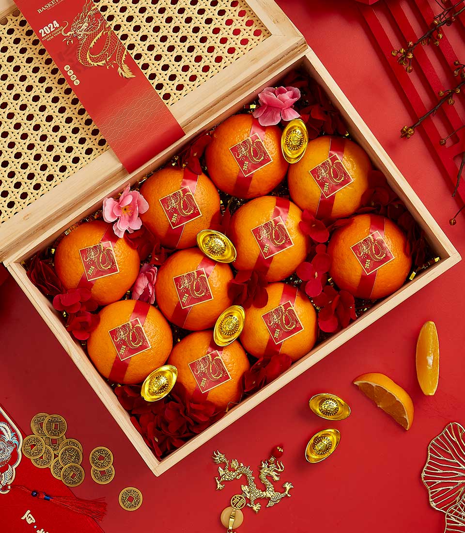 Basketeer luxury gift basket Bangkok, overflowing with oranges and gold ingots in a wooden crate, adorned with red ribbons for Chinese New Year. A premium hamper delivery in Thailand.