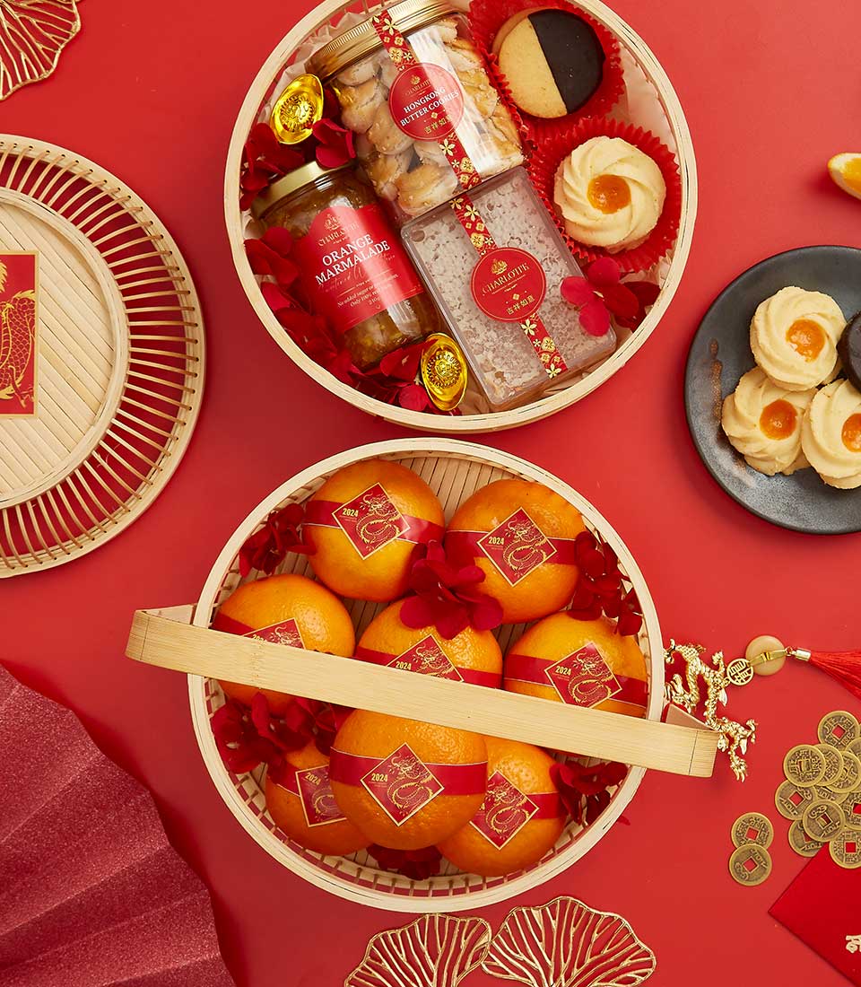Woven bamboo gift baskets with orange marmalade, butter cookies, mandarins, and gold dragon charms for Chinese New Year