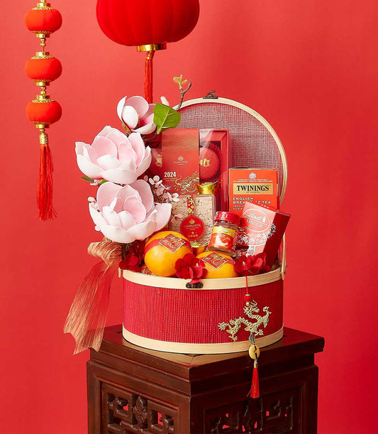 Red bamboo gift basket with dragon charm, oranges, Twinings tea, Lindt chocolates, lotus flowers and lucky lanterns for