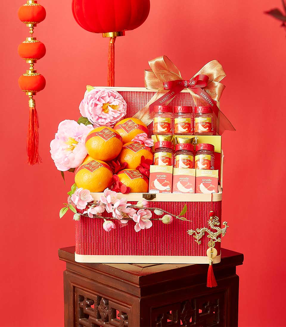 Red Chinese New Year hamper with citrus, gold ribbon bow, and prosperity charms on festive display