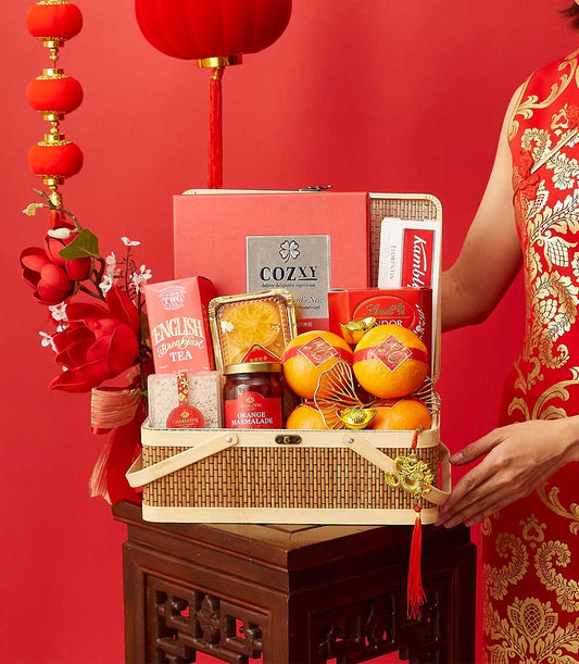 Luxury Chinese New Year gift basket with tea, chocolate, marmalade, and festive red accents on woven bamboo