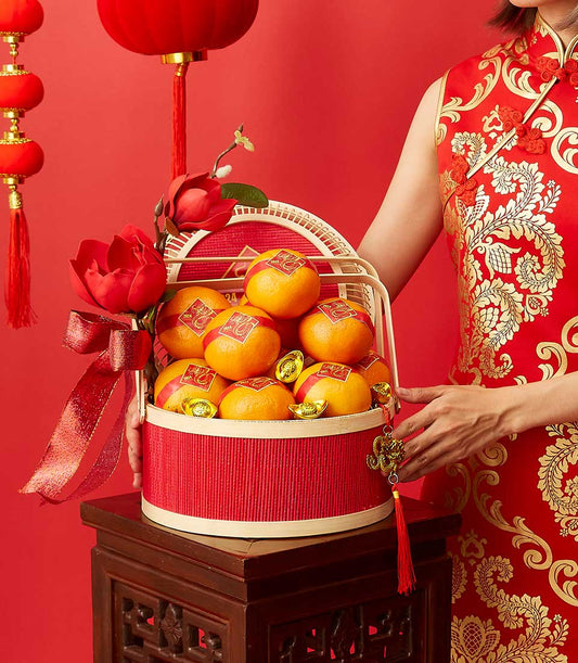 Festive red and gold Chinese New Year gift basket with fresh oranges, gold ingots, and lucky charms