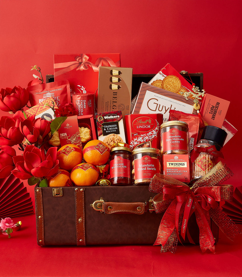 Luxury CNY gourmet hamper in vintage brown suitcase with red and gold packaged chocolates, biscuits, tea, and fresh