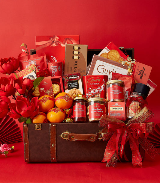 Luxury CNY gourmet hamper in vintage brown suitcase with red and gold packaged chocolates, biscuits, tea, and fresh