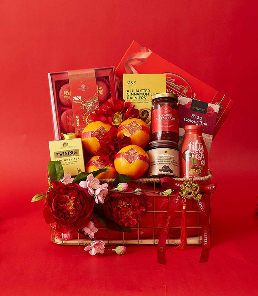 Festive red Chinese New Year gift basket with pastries, tea, chocolate, and fresh flowers