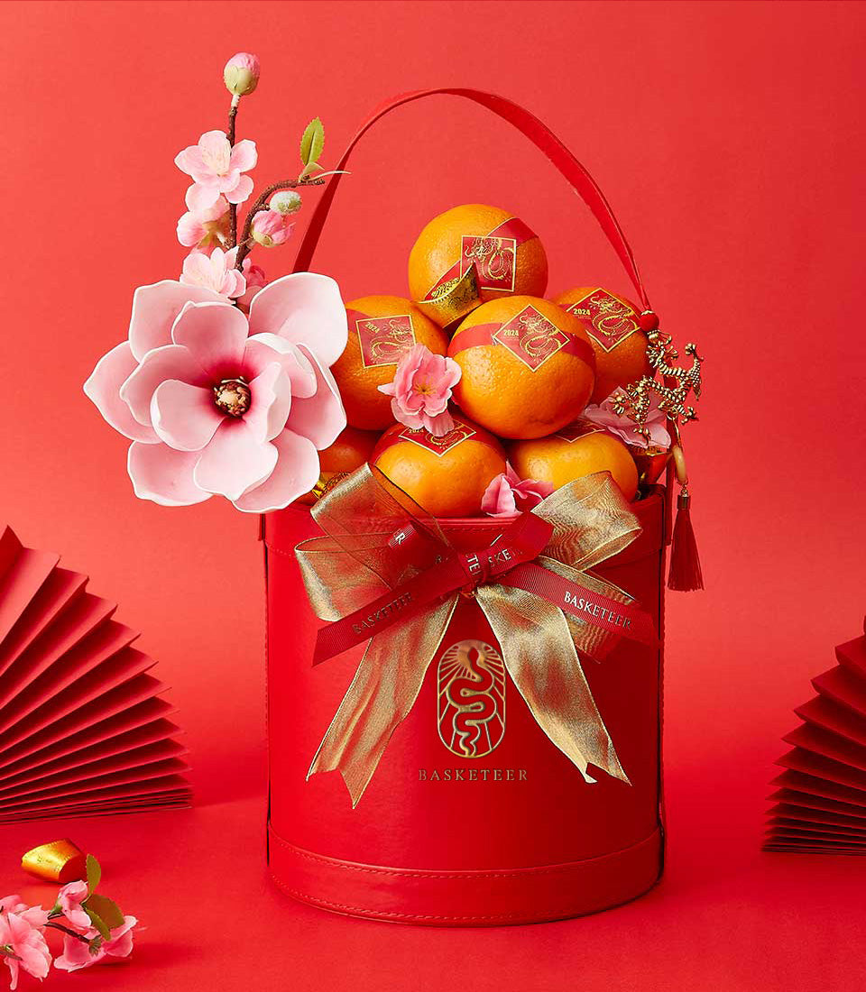 Festive red gift box with mandarin oranges, pink and white flowers, and gold ribbon for Chinese New Year