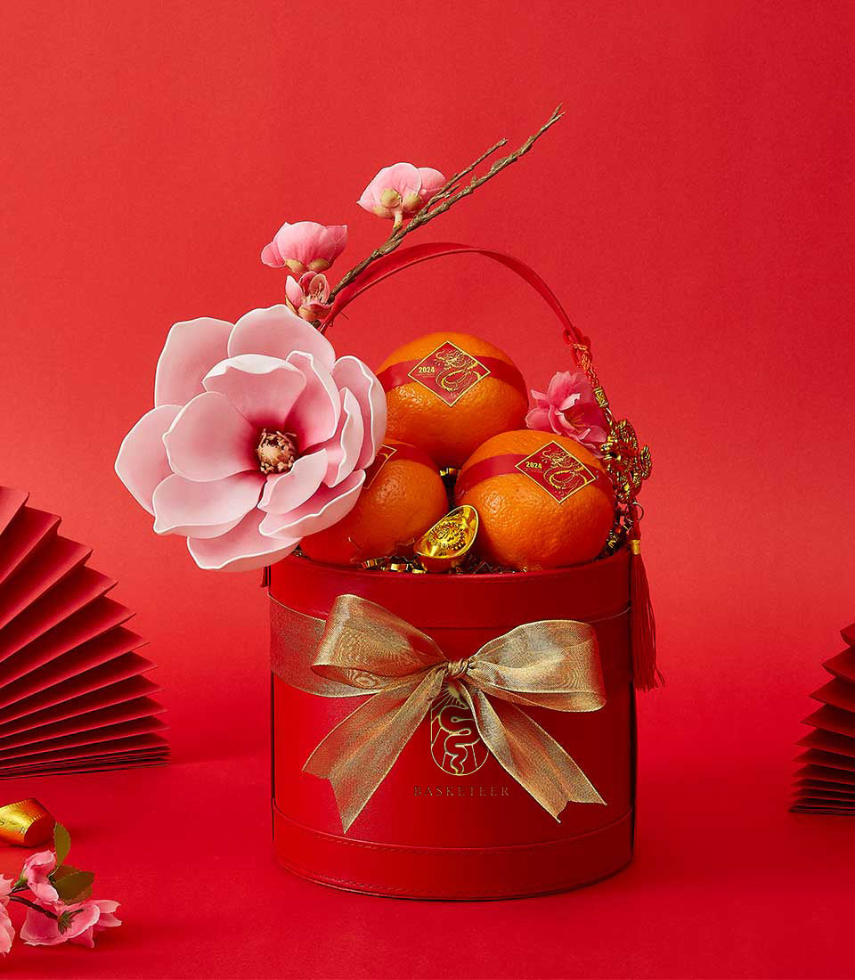 CNY orange luxury gift box with dragon stickers, gold accents, and pink flowers on red festive background