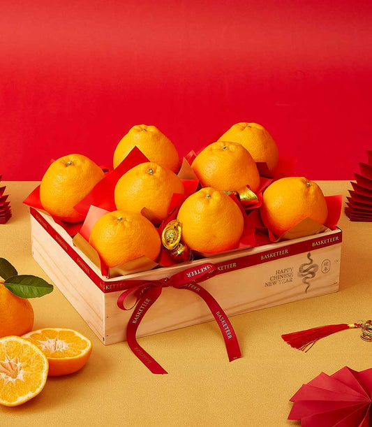 Wooden gift box filled with nine bright dekopon oranges, red tissue paper, and red ribbon with "Happy Chinese New Year"