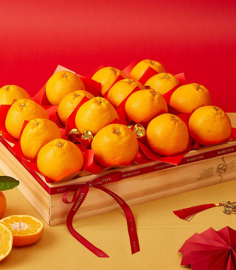 Wooden gift box filled with Dekopon oranges and gold ingots, red ribbon wrap, Chinese New Year celebration basket