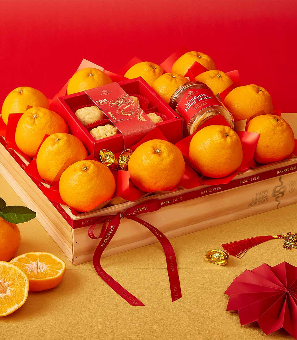 Festive red gift box with bright mandarins, cookies, and mandarin swirls for Chinese New Year celebrations